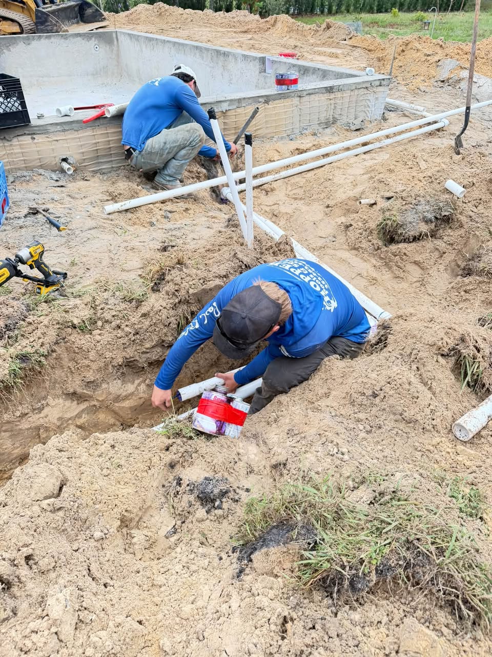 Hopper Pools family crew installing pool plumbing on a job site