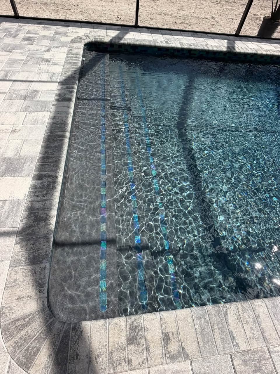 Sun shelf steps and decorative pool tile under clear water